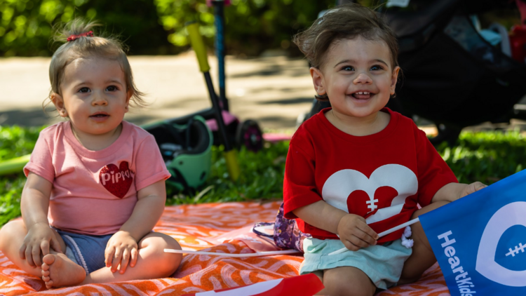 Two kids smiling on a picnic rug