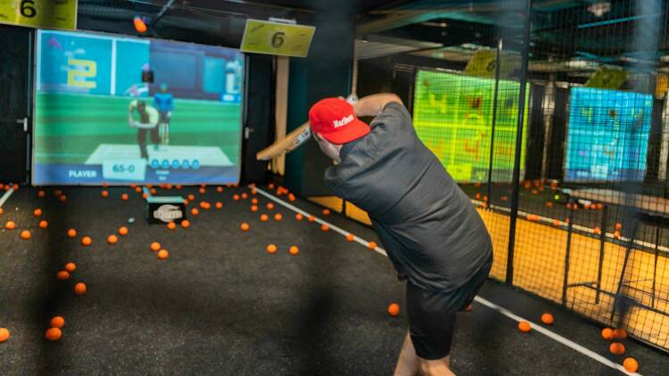 A man playing indoor simulated cricket.
