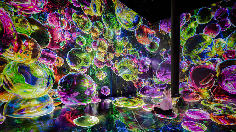 A purple and green digital projection of bubbles at ARTECHOUSE.