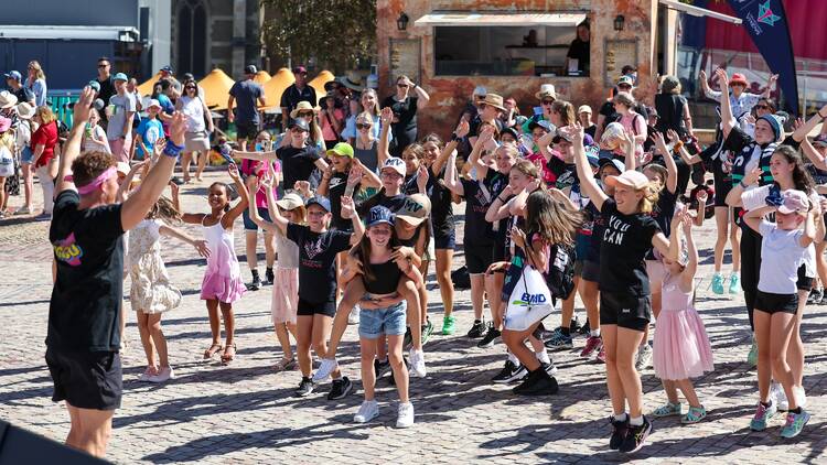 A group of children dancing at Federation Square. 