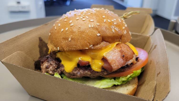 A hamburger with cheese, bacon, lettuce and tomato.