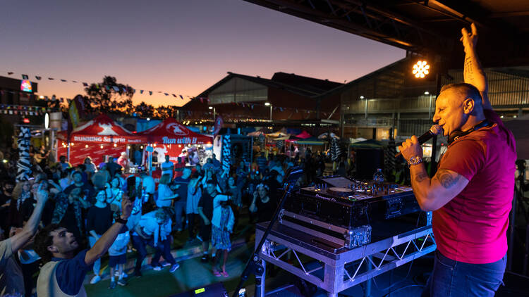 A DJ performs at a market at night.