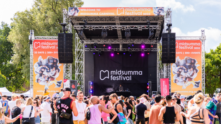 A stage at Midsumma Carnival with a crowd socialising