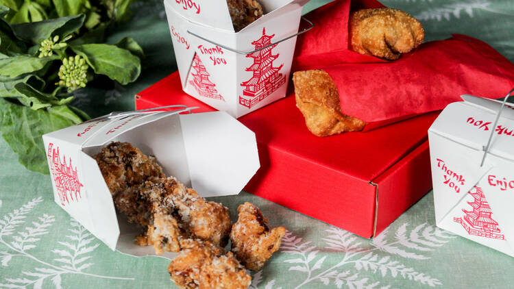 Fried chicken in take out containers with wrapped egg rolls