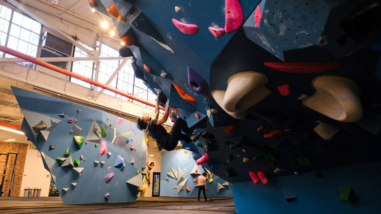 A person climbs a wall in a bouldering gym.