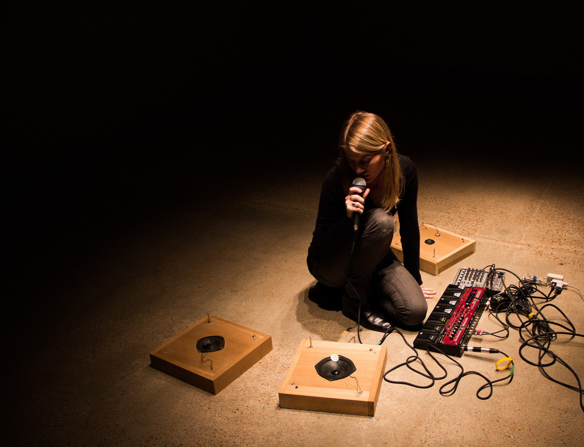 A woman sits with audio equipment.