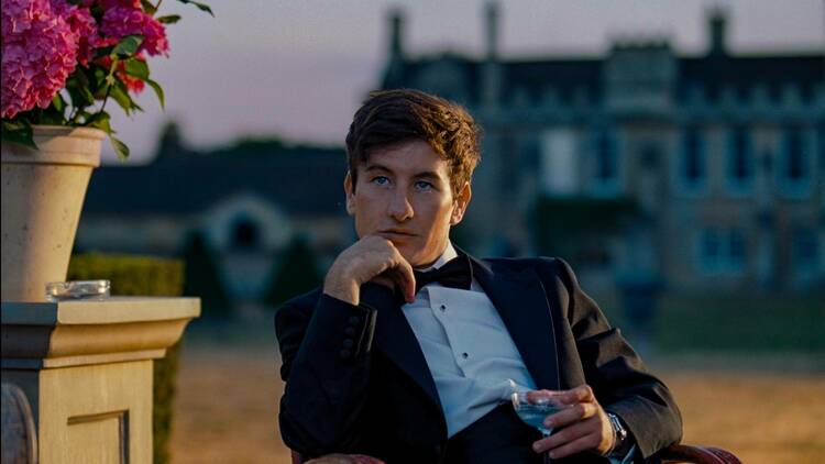 Barry Keoghan as Oliver Quick in ‘Saltburn’ sits nursing a drink wearing a suit and bowtie