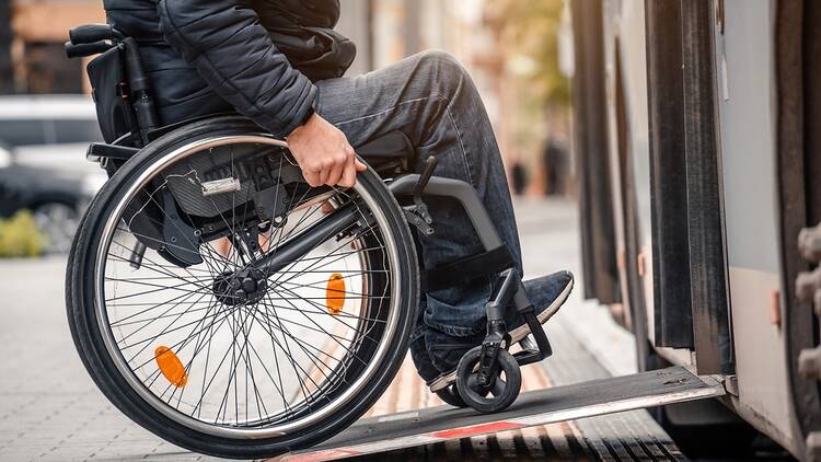 Person on a wheelchair uses a ramp to get on a bus