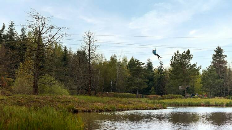 A person uses a zipwire over a lake at Center Parcs Les Trois Forêts, France