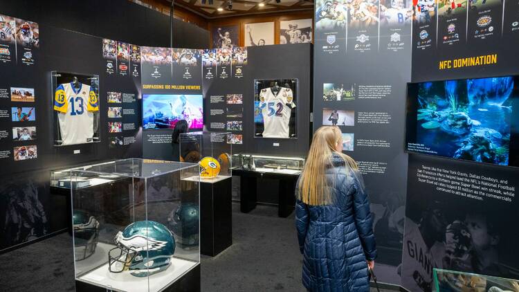 A woman walks through a museum exhibit with football memoriabillia