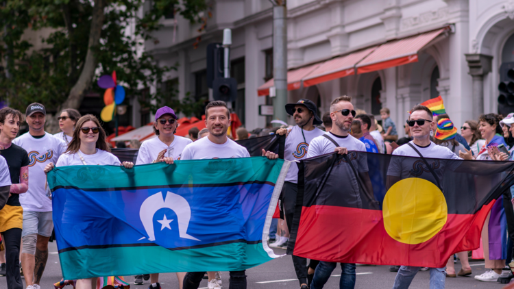 People hold the Aboriginal and Torres Strait Islander flags at the Midsumma Pride March