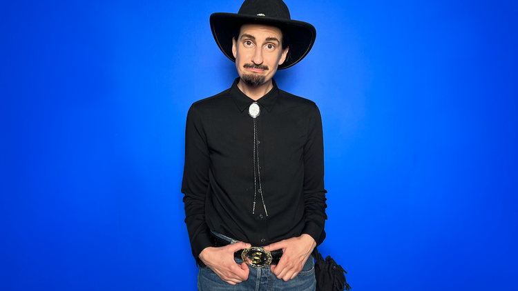 Comedian with cowboy hat against blue background