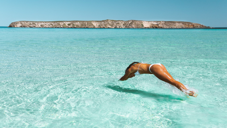 Woman dives in blue water at Almonta Beach