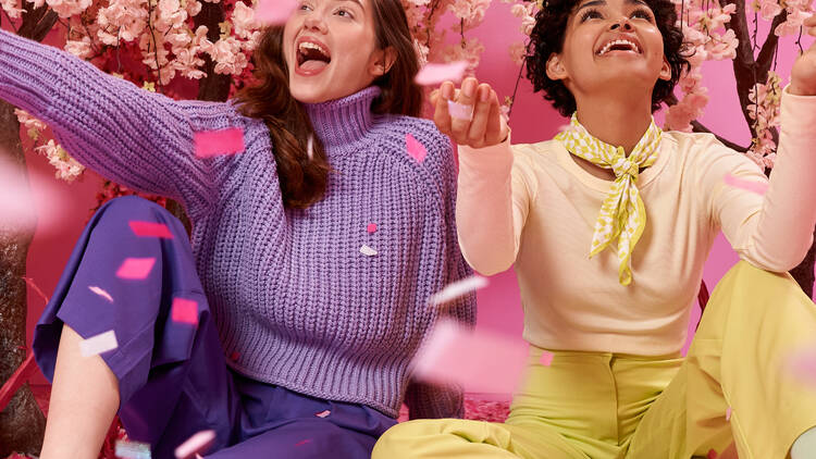 Two women play in pink confetti.