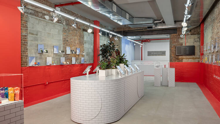 The inside of a cannabis store with a white counter and red walls.