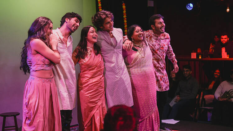 A group of performers on stage in pink outfits.