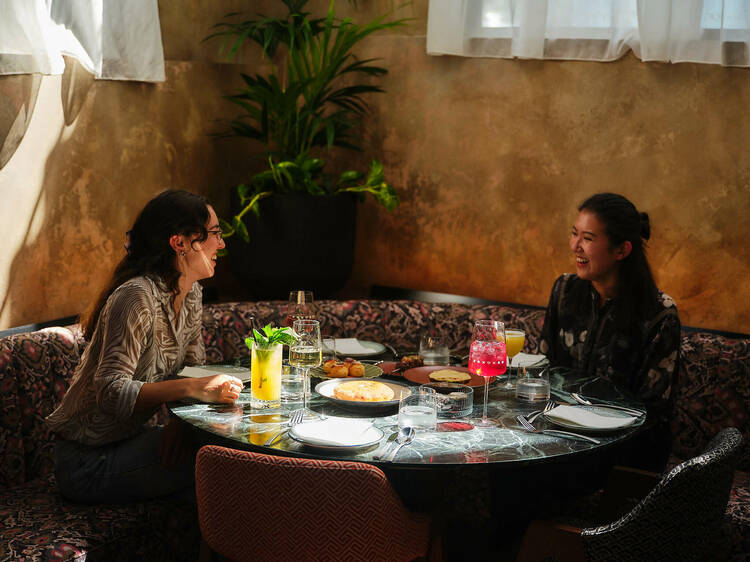 Laughing women sitting around a food and drink-laden table at Pincho Disco.