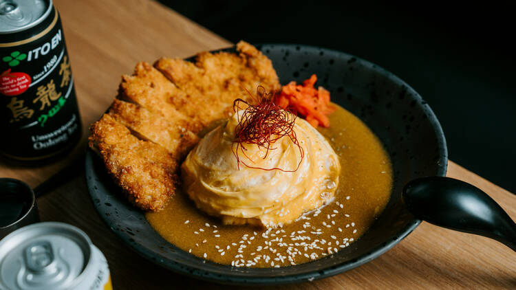 A bowl of omurice with pork katsu and golden curry sauce.
