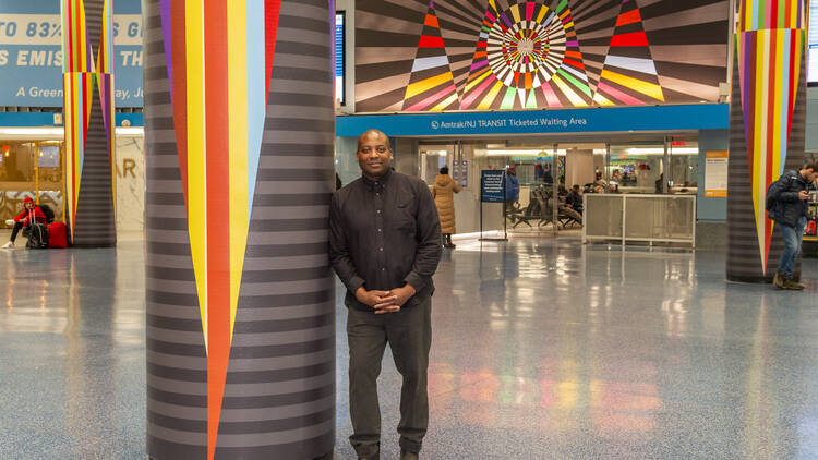 artist stands in front of his art in train station 