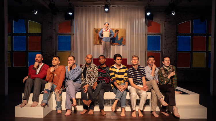 Nine men sit in a row looking pensive in The Inheritance