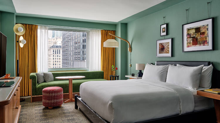 A guest room with a bed and green couch.