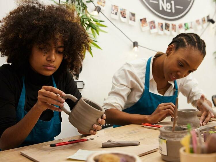 Two women work on making pottery.