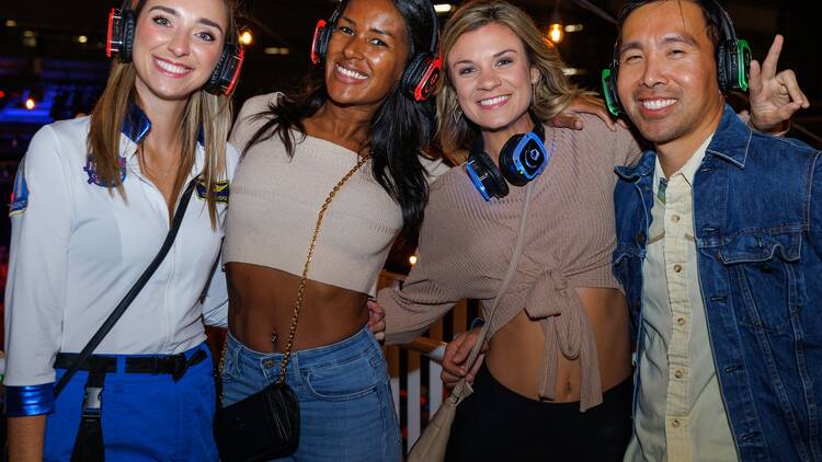 Four people at a silent disco event wearing over-ear headphones.