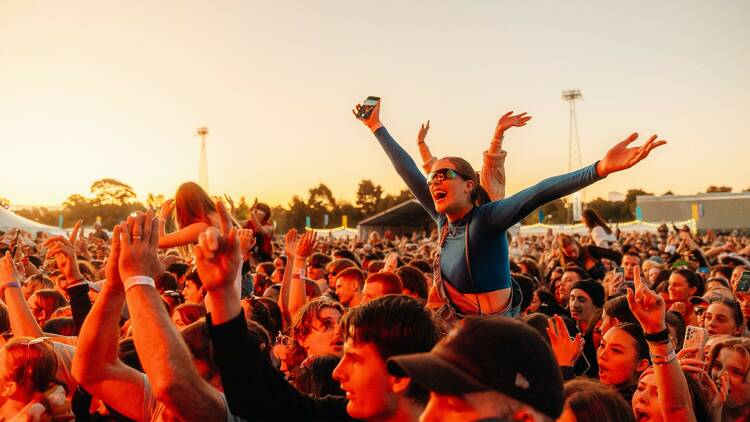 Person up on someone's shoulders at GTM, cheering with their arms raised