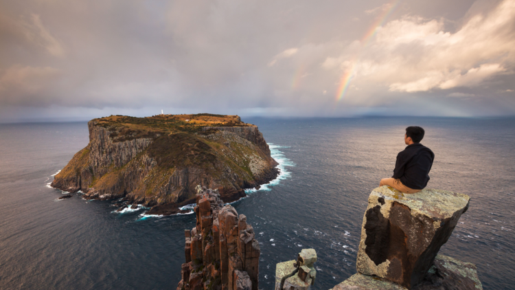 Person sitting on rugged rocks overlooking ocean