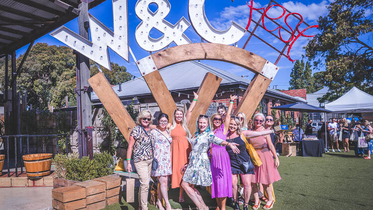 A group of women posing at the entrance to the Wine and Cheese Fest.