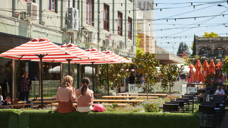 Two women sit in the busy Yarraville precinct.