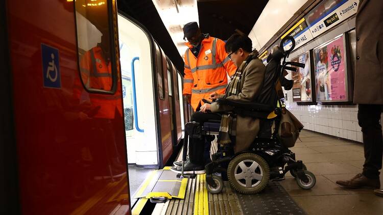 A man in a wheelchair using a ramp to board a train on the Victoria line 