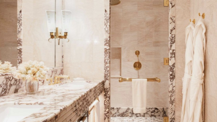 Marbled bathroom with robes hanging up in Hotel Barrière Fouquet's hotel