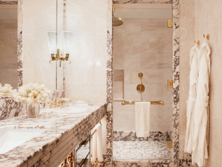 Marbled bathroom with robes hanging up in Hotel Barrière Fouquet's hotel