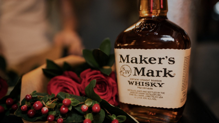 A bottle of Maker's Mark Whisky next to a bouquet of flowers