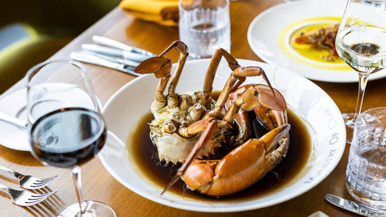 A crab dish served with a glass of red wine.