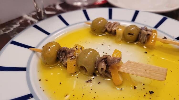 Little sticks with olives, anchovies and bits of lemon on a bed of oil.