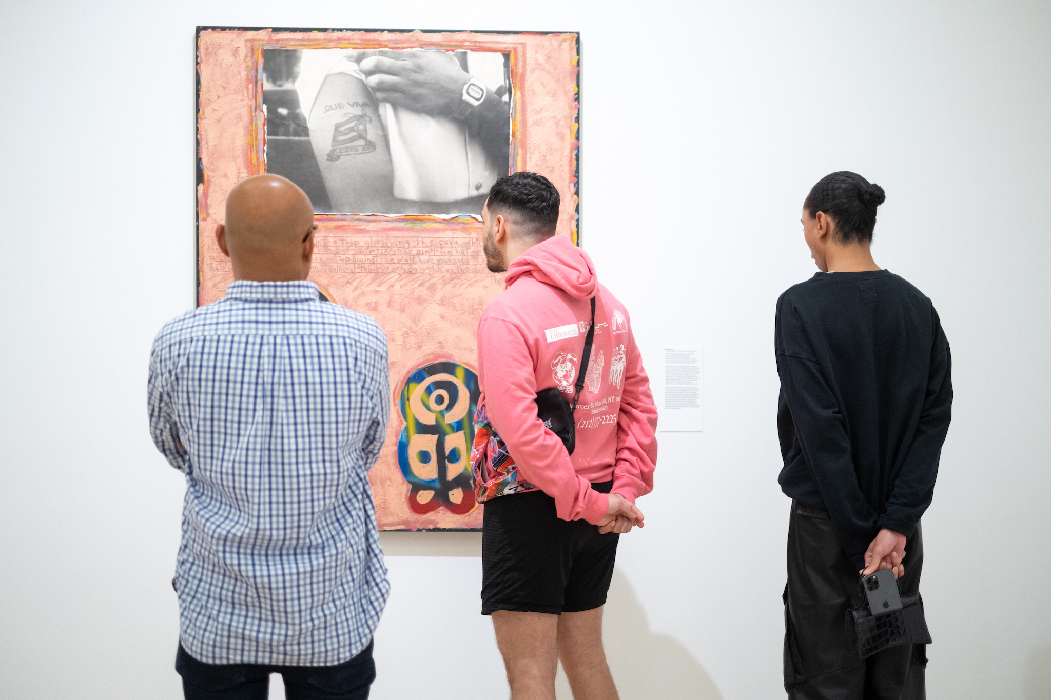 A group of people look at a painting on a wall.