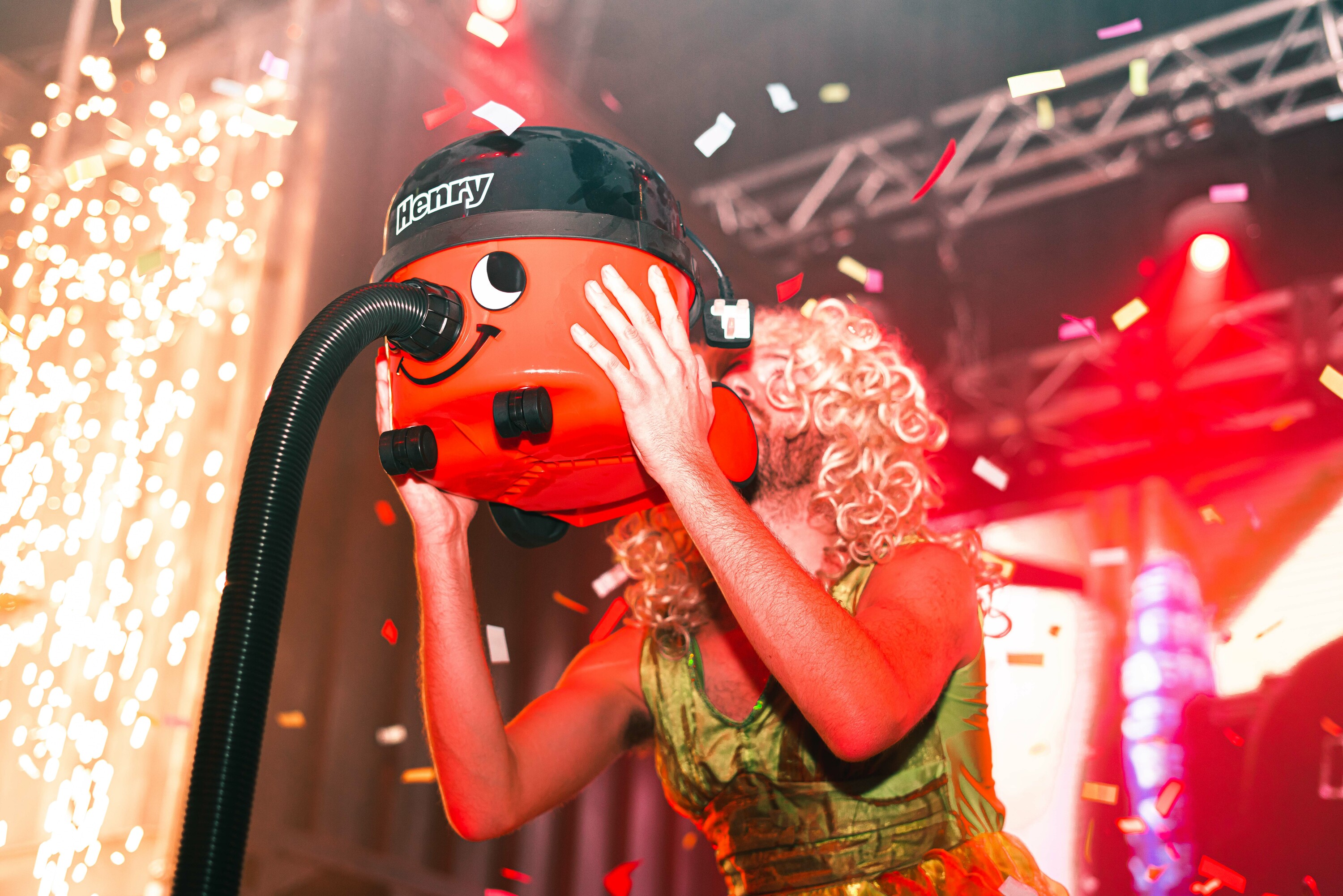 A person on stage with a Henry Hoover vacuum.