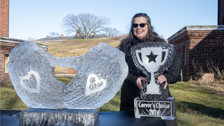 Woman stands with ice sculpture and a trophy