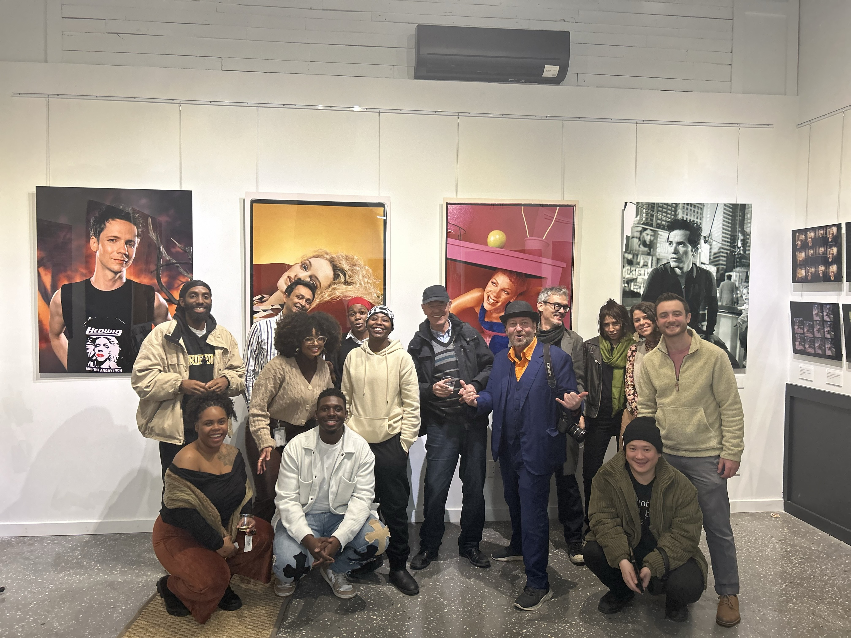 People pose in front of artwork in a gallery