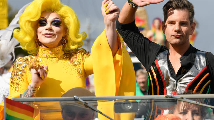 People waving to a crowd from a street parade float. 