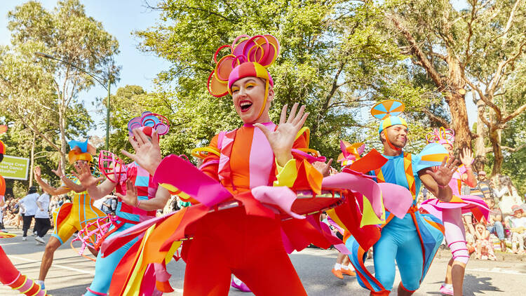 People dancing in a parade in colourful outfits. 