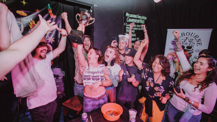 Spectators cheering for the trophy-carrying champion at the B.East's chilli eating competition.