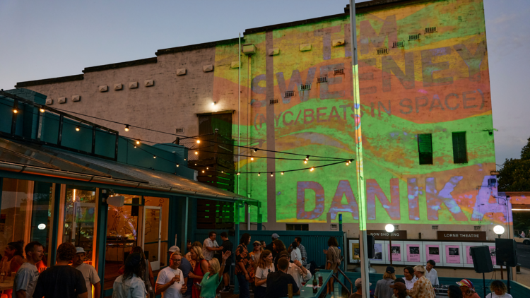 A beer garden with bright projections on a tall wall.