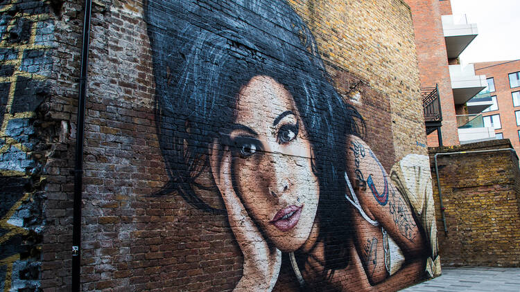 a colourfully painted mural of Amy Winehouse on brick wall