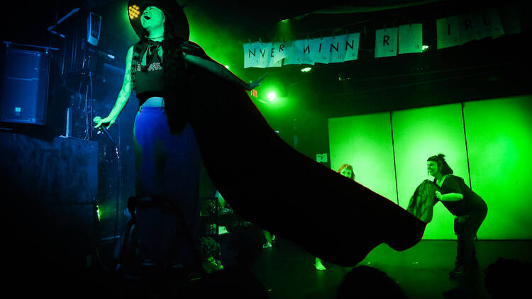 a person sings on stage with a large cape