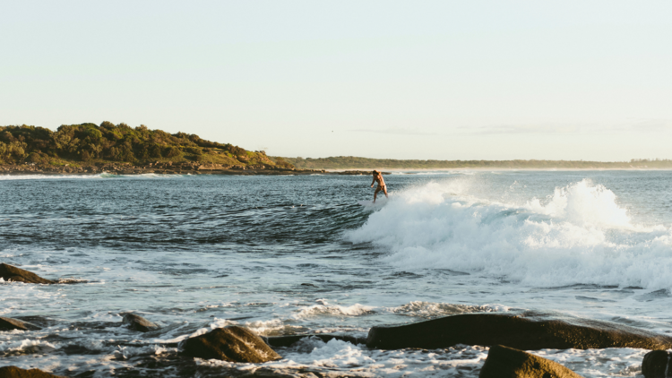 Woman enjoying a morning surf at Angourie Point Beach, Angourie.