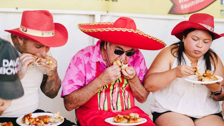 People in red hats eating food with chilli in it.