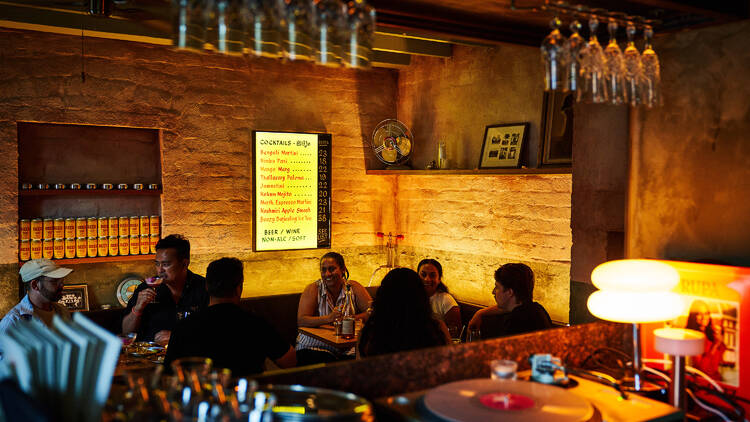 Guests gathered around tables within the warmly lit interior of Toddy Shop.